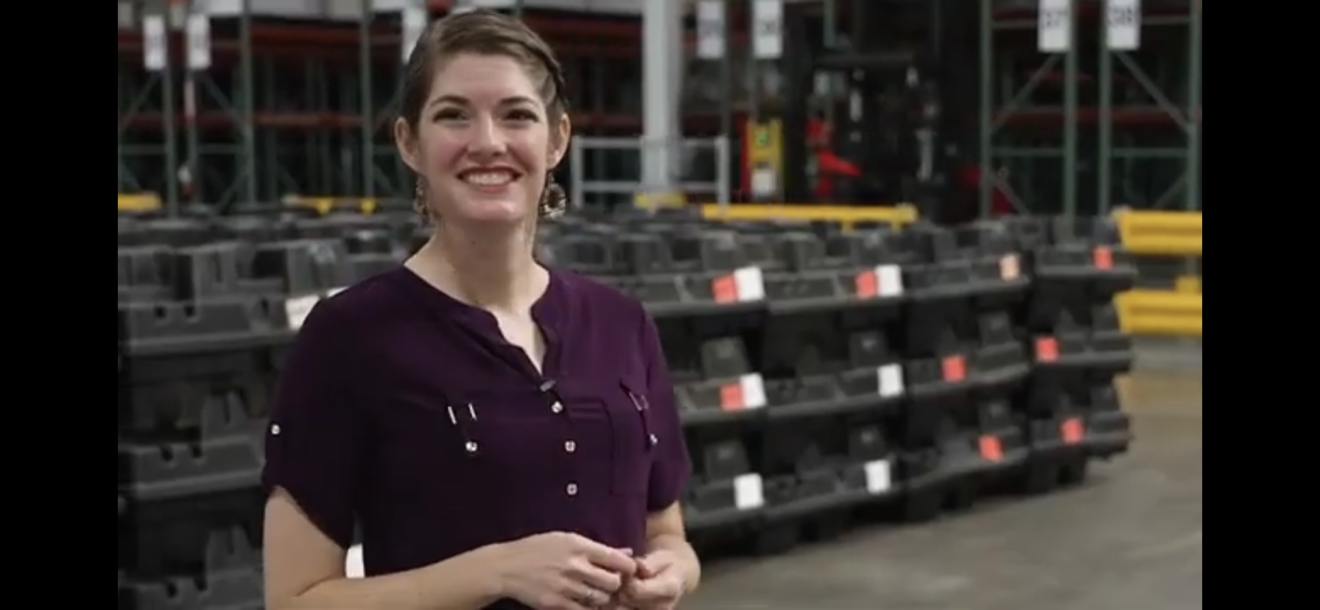 Raelene smiles in the warehouse with an excited expression on her face.
