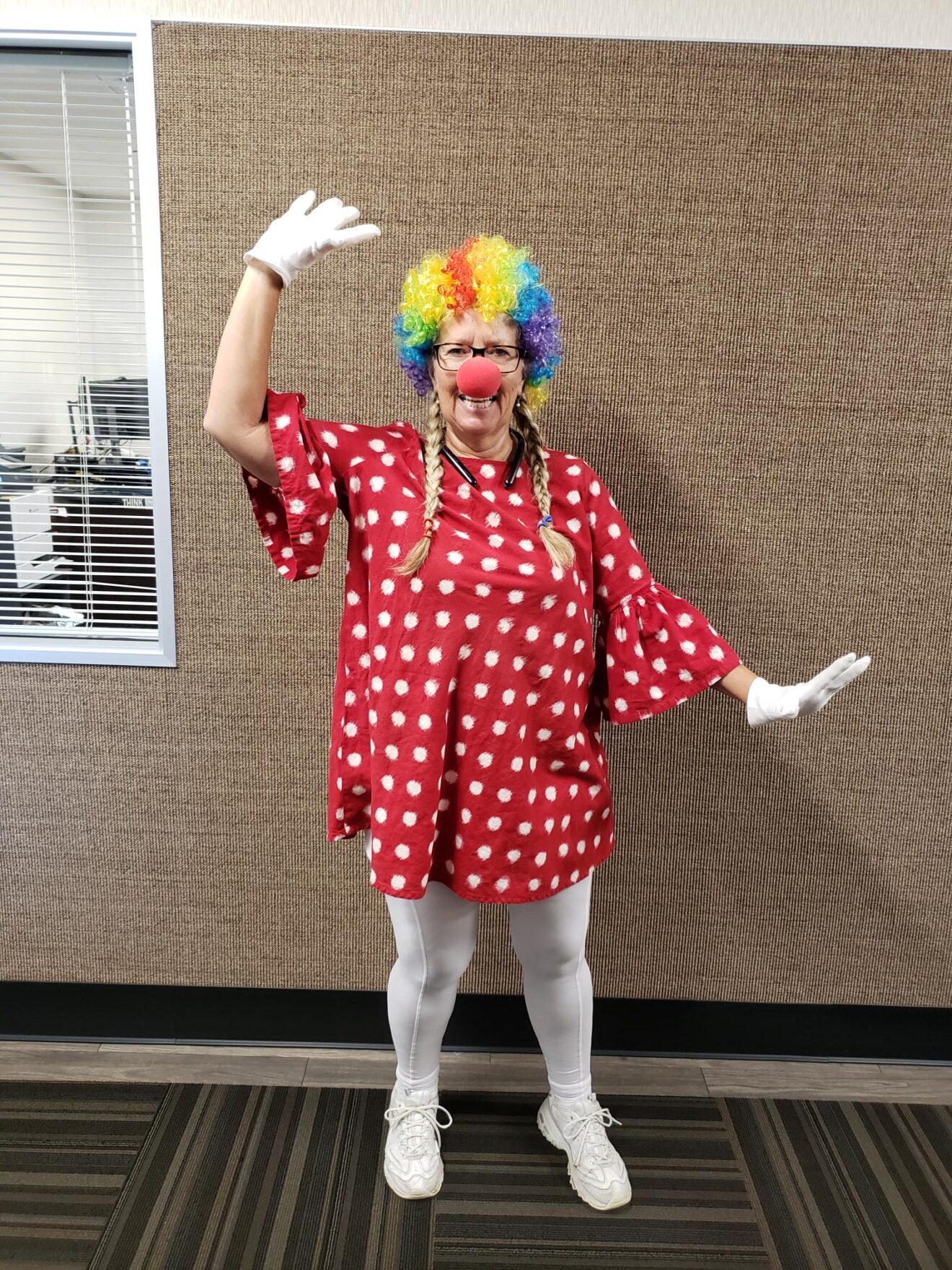 Cristy in a long red tunic with white polka dots and a rainbow wig.